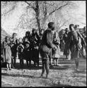 Man and woman dancing while a group of people sings; expedition truck in background