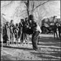 Man and woman dancing, and group singing and clapping, with expedition truck in background