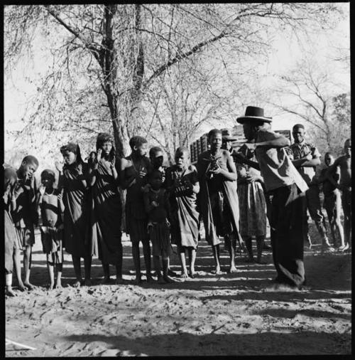 Man dancing, with group of people singing and clapping in background