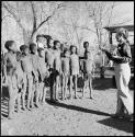 Group of children standing, and Lorna Marshall taking a light reading