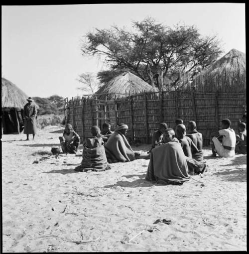 Group of women sitting outside one of the village fences