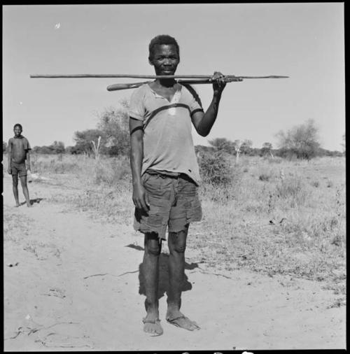 Man with a beard standing and holding an assegai and a club