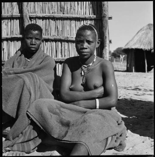 Two women sitting by a fence