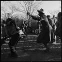 Men dancing, with group of people singing in background