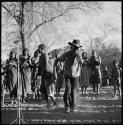 Man wearing a black hat and dancing, with group of people singing in background; microphone seen on the left