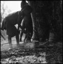 Girl standing in front of skerm and stirring something cooking on a fire