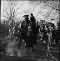 Man and woman dancing, with group of people singing in background