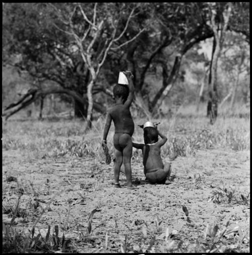 Two children holding a pan and a can on their heads