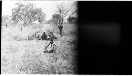 Man sitting in the grass (image partly obscured)