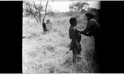 Man pressing his hands against ≠Toma's chest (image partly obscured)