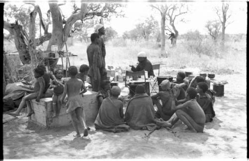 Kernel Ledimo, Philip Hameva, and a group of Ju/'hoansi, including ≠Toma, gathering in a cluster