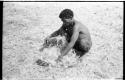 ≠Toma with a carrying net, squatting on the grass