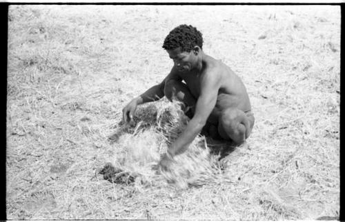 ≠Toma with a carrying net, squatting on the grass