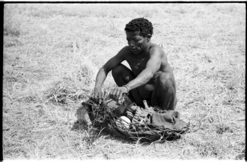 ≠Toma lining a carrying net with a small kaross to pack it with rattles, ostrich eggshells, etc.