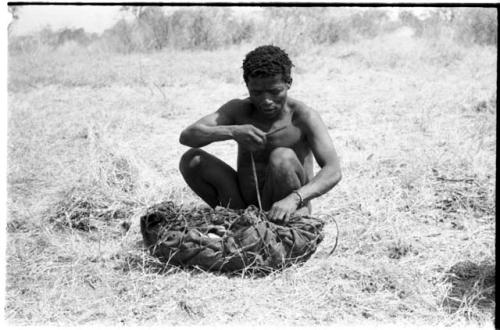 ≠Toma lining a carrying net with a small kaross to pack it with rattles, ostrich eggshells, etc.