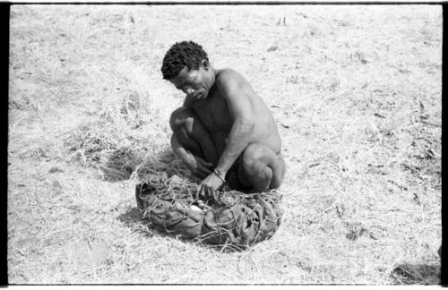 ≠Toma lining a carrying net with a small kaross to pack it with rattles, ostrich eggshells, etc.