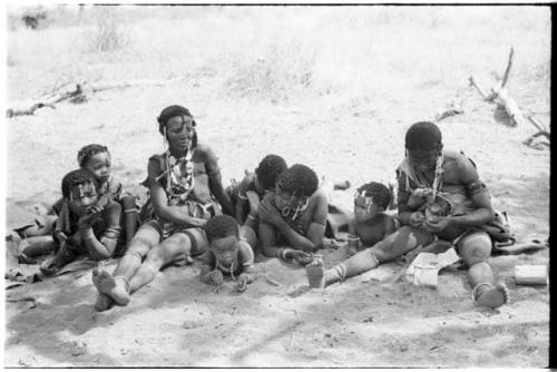 Group of women and children lying and sitting on the ground, including  /Goishay (wife of ≠Gao) on extreme left