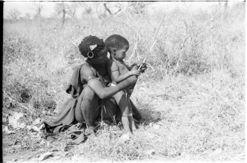 Di!ai showing her son Debe how to make an arrow