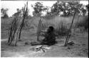 Woman seated by her fire, holding a child