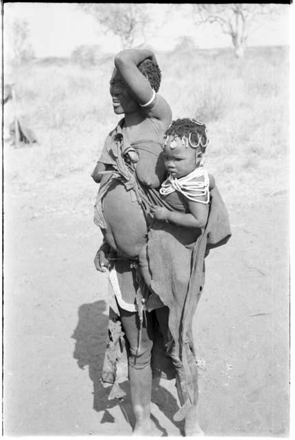 Woman with a child tied in her kaross, showing modesty apron of leather with a beaded border