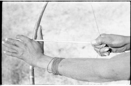 Hands of "Crooked /Qui," showing position of hand on bow and right hand pulling back the bow string