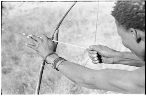 Hands of "Crooked /Qui," showing position of hand on bow and right hand pulling back the bow string