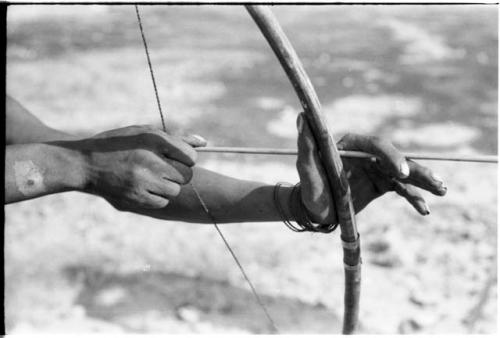 Close-up of "Crooked /Qui's" hands, showing arrow release and position of left hand on bow