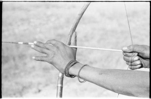 Close-up of "Crooked /Qui's" hands, showing arrow release and position of left hand on bow