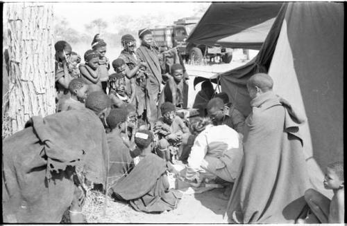 Group of Ju/'hoansi, Kernel Ledimo, Lorna Marshall gathered around to look at beads, seemingly in the cold