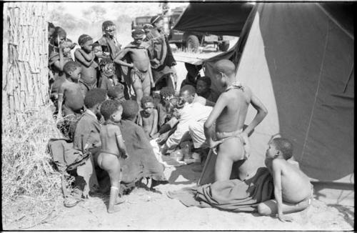 Group of Ju/'hoansi, Kernel Ledimo, Lorna Marshall gathered around to look at beads, seemingly in the cold