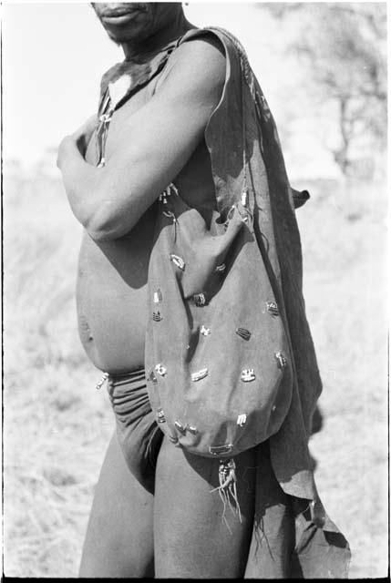 Man wearing a breechclout, bag ornamented with beads, and small kaross