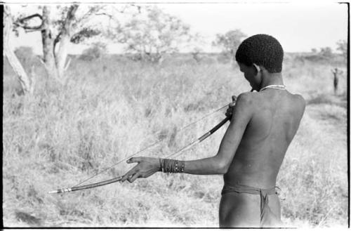 !Naishi (brother of /Goishay) playing a musical bow, seen from behind