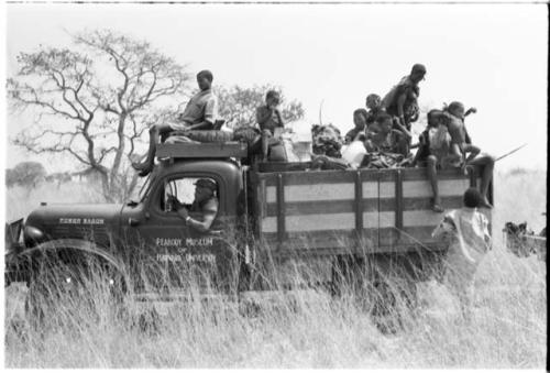 Truck loaded with a group of Ju/'hoansi on top, with Heinrich Neumann behind the wheel