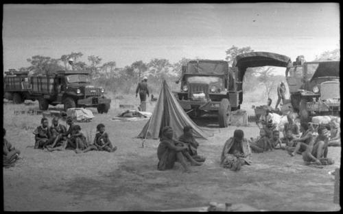 Group of Ju/'hoansi in front of the tents and trucks at the expedition camp