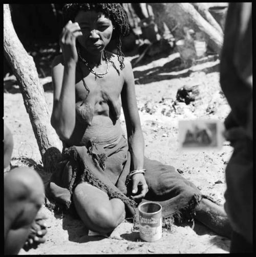 Tshombe, wife of _Tao or Daou sitting, with a can on the ground in front of her