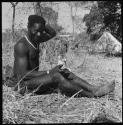 Bela cleaning wart-hog tusks, with tents in background