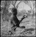 Bela cleaning wart-hog tusks, wearing turban and shirt