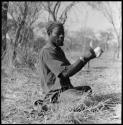 Bela cleaning wart-hog tusks, wearing turban and shirt