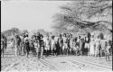 Group of people, including a police officer, standing in the road at Tsau