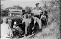 Group of men working on stuck expedition trucks