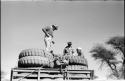 Simon Molamo, Casper Kruger and another person sitting and standing on top of GMC tires on the top of an expedition truck