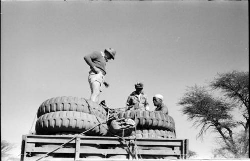 Simon Molamo, Casper Kruger and another person sitting and standing on top of GMC tires on the top of an expedition truck