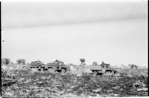 Expedition trucks waiting in burned-over land