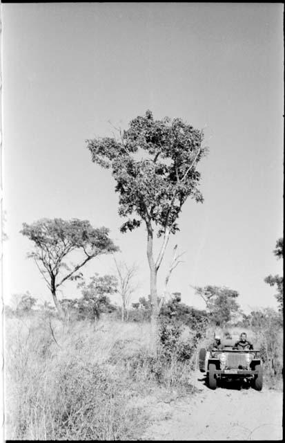 Simon Molamo and William Donnellan sitting in the expedition Jeep on a road