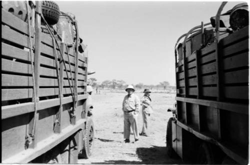 Laurence Marshall and Lorna Marshall standing between two expedition trucks