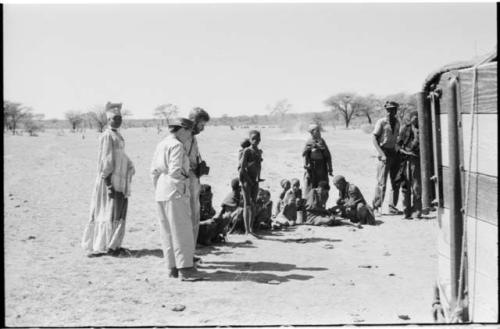 Group of people sitting and standing, including a Herero woman, Laurence Marshall and Daniel Blitz