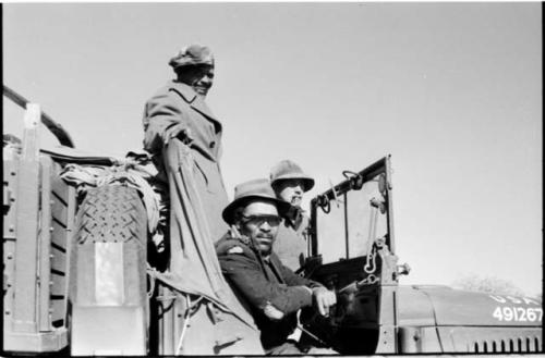 Heinrich Neumann standing, and Wilhelm Camm and Casper Kruger sitting inside an expedition truck