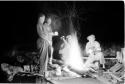 Expedition staff standing and sitting by a fire a night