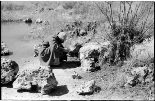 Robert Story wearing an overcoat and crouching to look at something