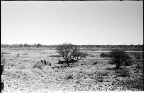 Distant view of a group of people, expedition Jeep and water